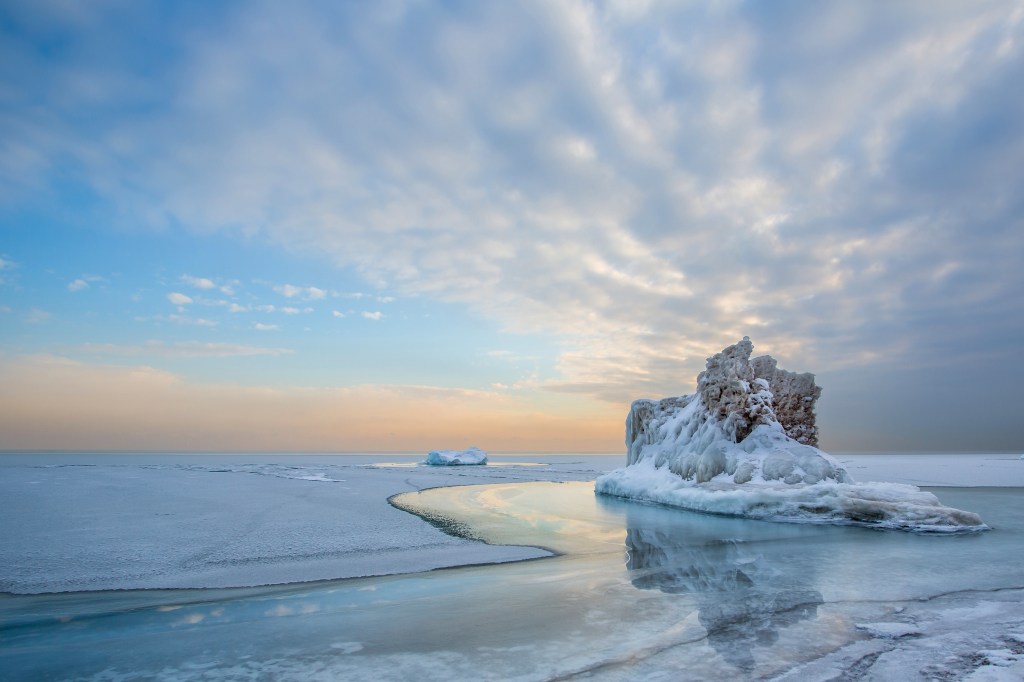 An iceberg floats in still waters under a half-clouded sky at Fort Sheridan.
