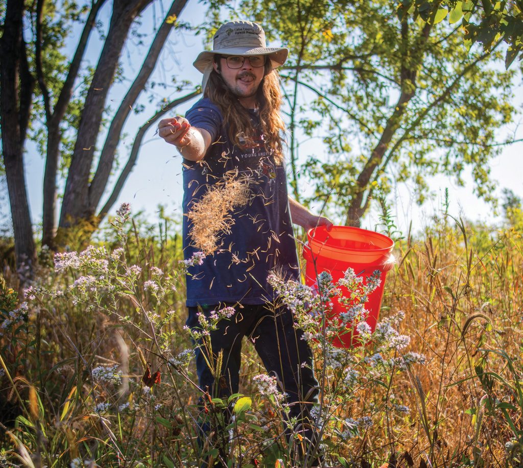 Volunteer site steward Mat Sullivan scatters native seed at Duck Farm in Lake Villa.